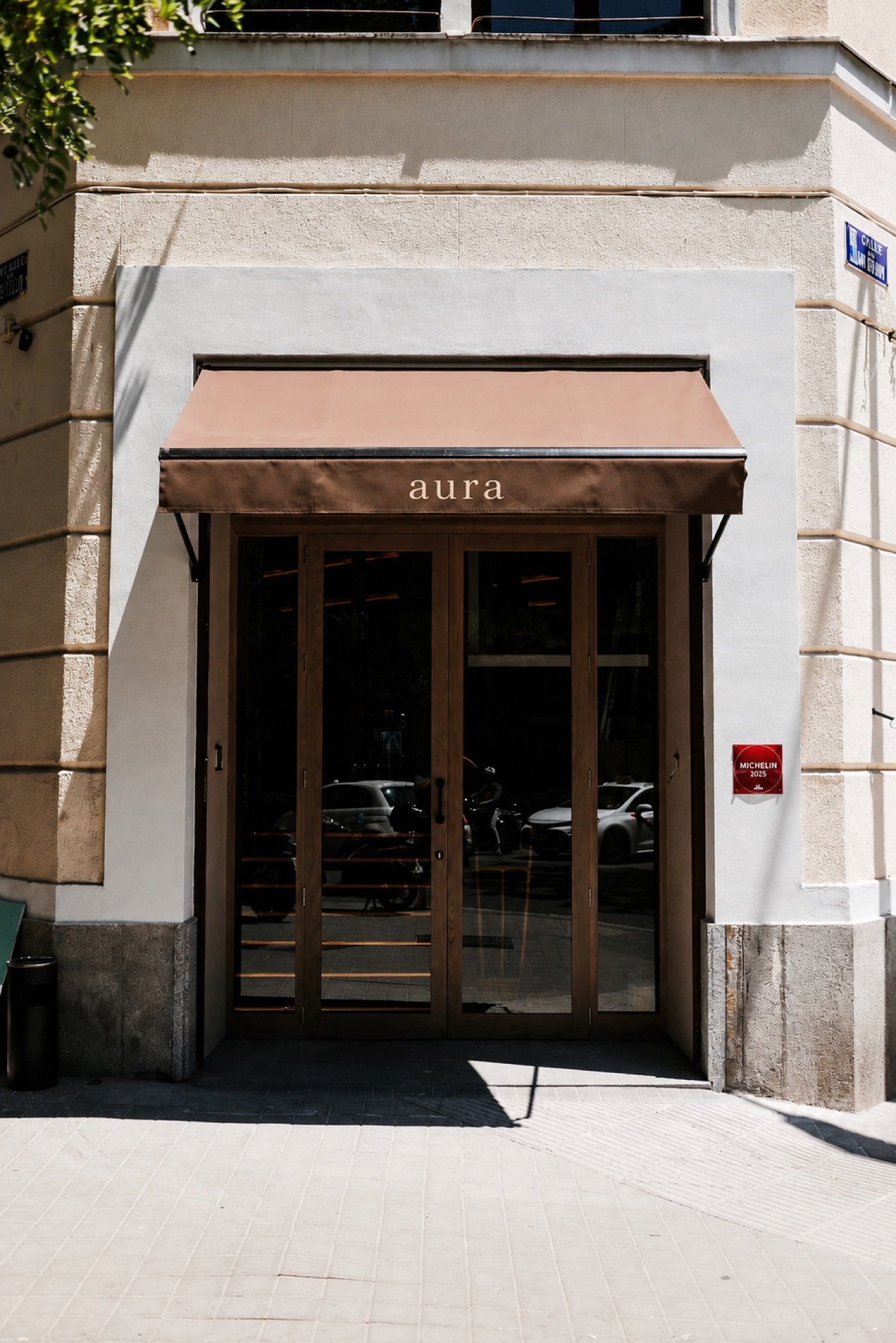 Fachada de AURA con toldo y puertas de madera en Calle Cádiz